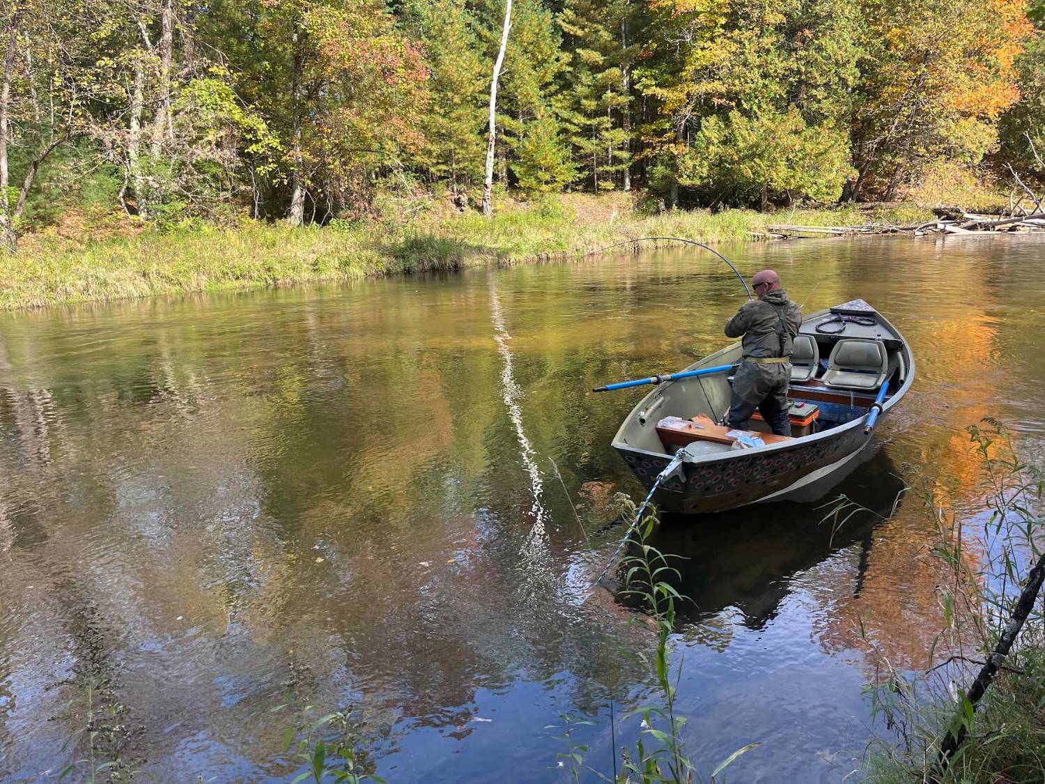 Angler with a bent rod playing a salmon from the drift boat